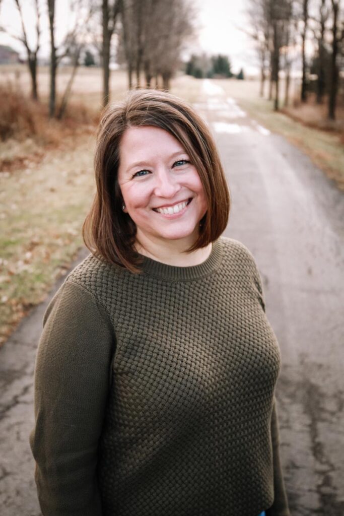 Wendy Herrmann standing on a path outdoors with trees behind her.